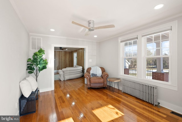 sitting room featuring crown molding, ceiling fan, radiator, and hardwood / wood-style flooring