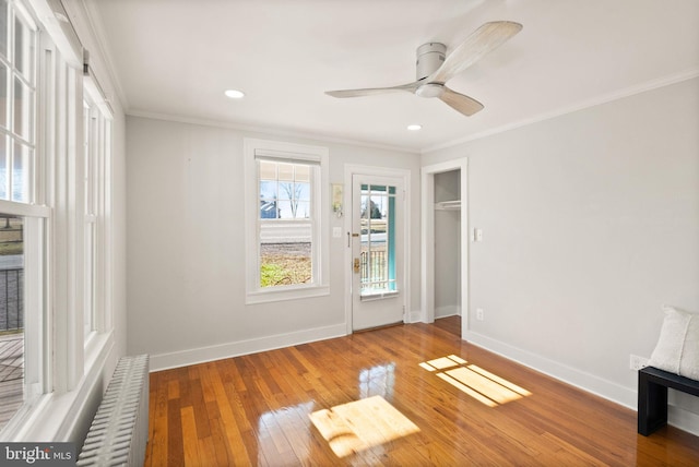 unfurnished room with ceiling fan, ornamental molding, radiator heating unit, and wood-type flooring