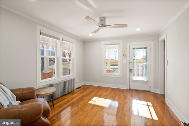 unfurnished room with hardwood / wood-style floors, ornamental molding, radiator heating unit, and ceiling fan