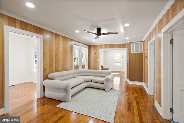 living room with hardwood / wood-style flooring, crown molding, and ceiling fan