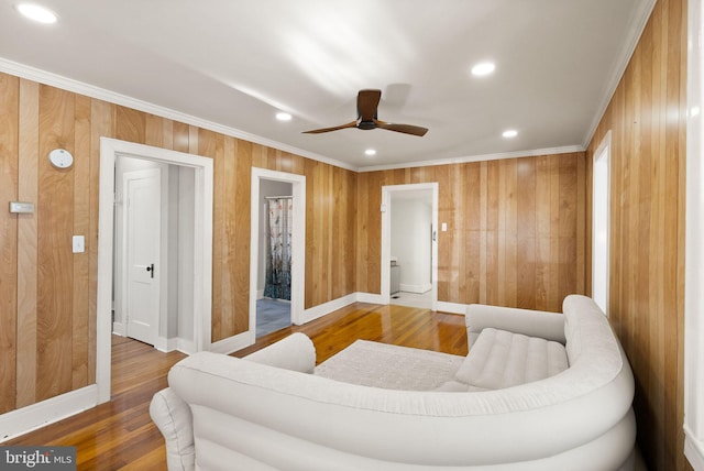 living room featuring ornamental molding, hardwood / wood-style floors, and wooden walls