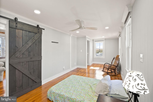 sitting room with crown molding, a barn door, ceiling fan, and light wood-type flooring