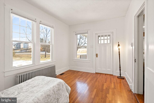 interior space featuring hardwood / wood-style flooring, radiator heating unit, and a textured ceiling