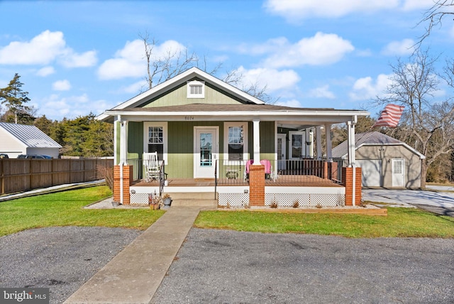 view of front facade featuring an outbuilding, covered porch, and a front lawn