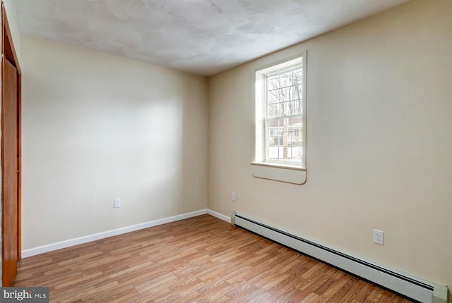 empty room featuring baseboard heating and light hardwood / wood-style floors