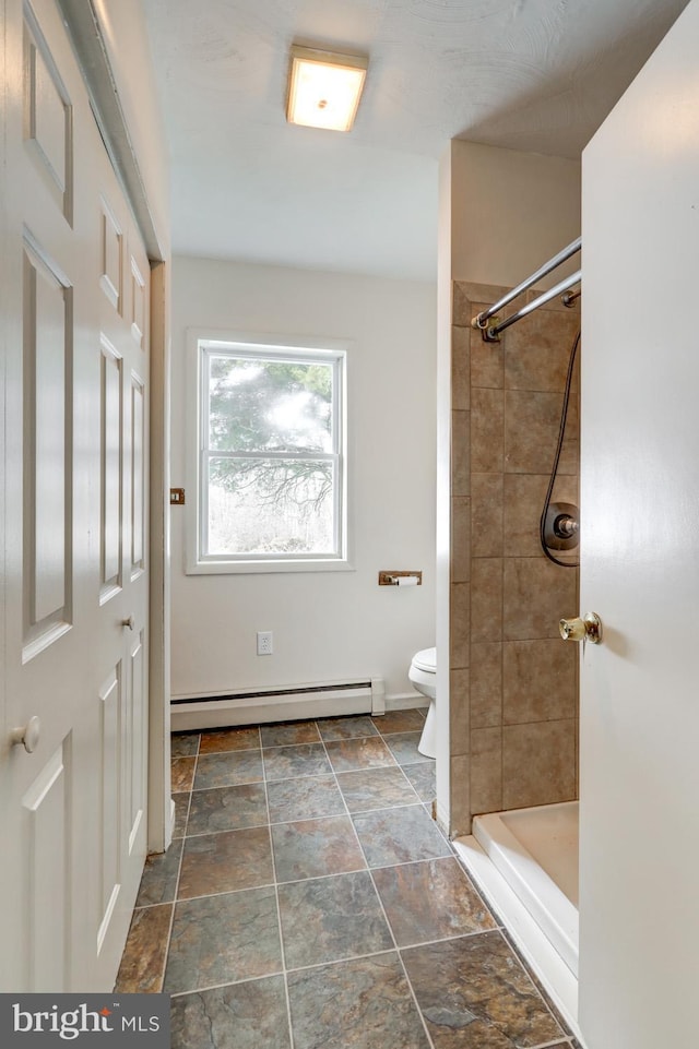 bathroom with a baseboard radiator, toilet, and a tile shower