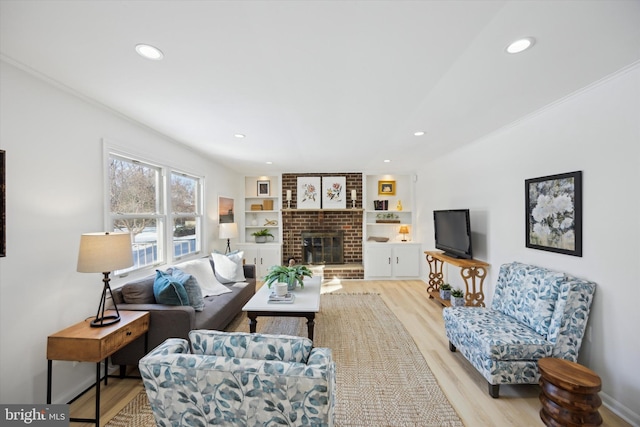 living room featuring built in features, a fireplace, and light hardwood / wood-style flooring