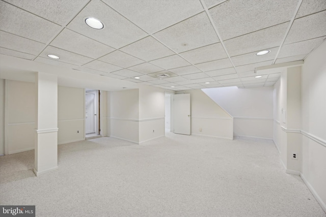 basement with a drop ceiling and light colored carpet