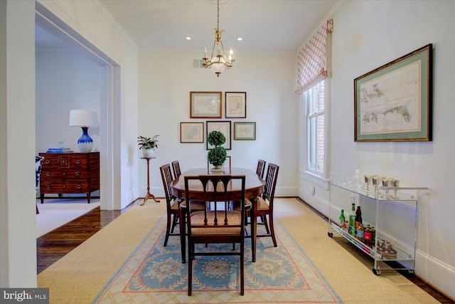 dining space with wood finished floors, recessed lighting, crown molding, baseboards, and a chandelier