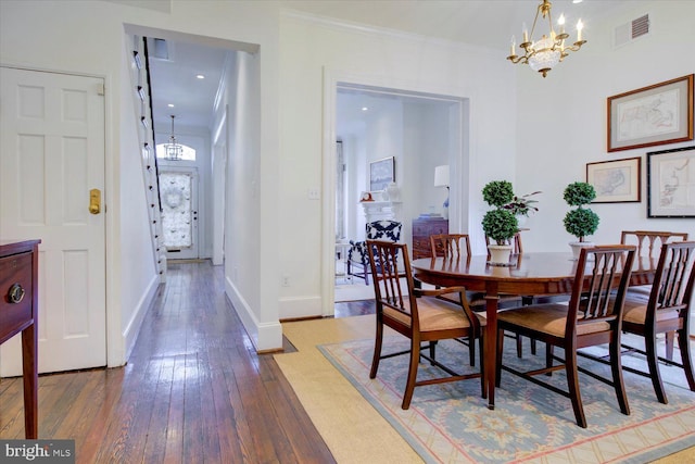 dining room with visible vents, baseboards, ornamental molding, hardwood / wood-style flooring, and a notable chandelier