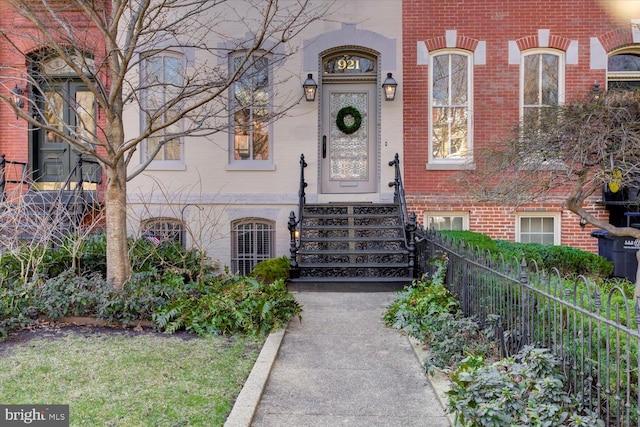 property entrance featuring fence and brick siding