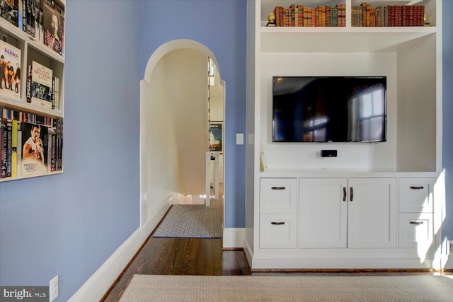 interior space featuring arched walkways, baseboards, and dark wood-style flooring