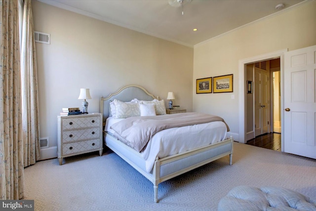 carpeted bedroom featuring visible vents, baseboards, and ornamental molding