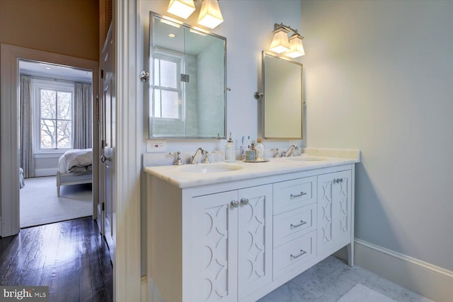 full bathroom featuring ensuite bath, double vanity, baseboards, and a sink