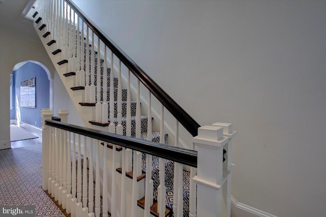 stairs with arched walkways, a high ceiling, and carpet