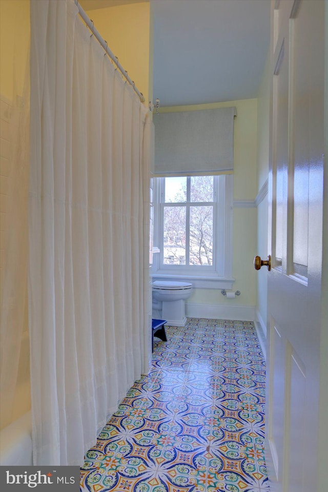 bathroom featuring tile patterned floors, a shower with curtain, baseboards, and toilet