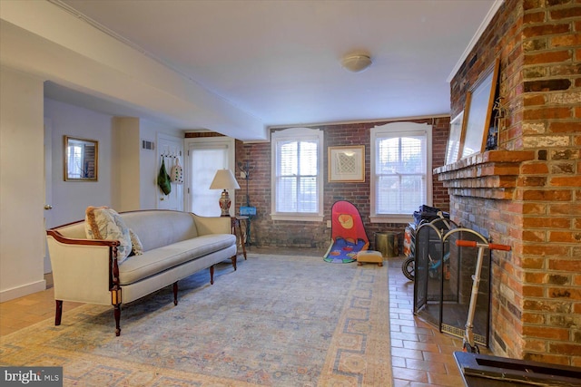 living room featuring visible vents, baseboards, and brick wall