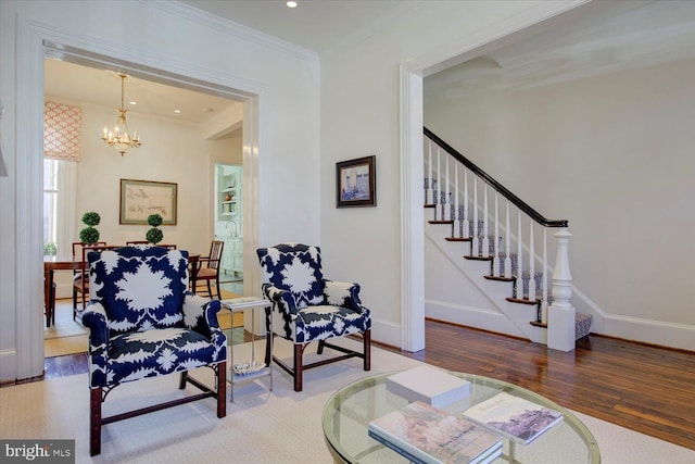 living area with stairway, wood finished floors, baseboards, ornamental molding, and a chandelier