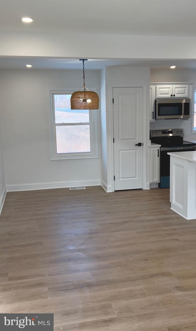 unfurnished dining area featuring light wood-type flooring