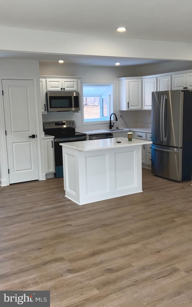 kitchen featuring appliances with stainless steel finishes, light hardwood / wood-style flooring, and white cabinets