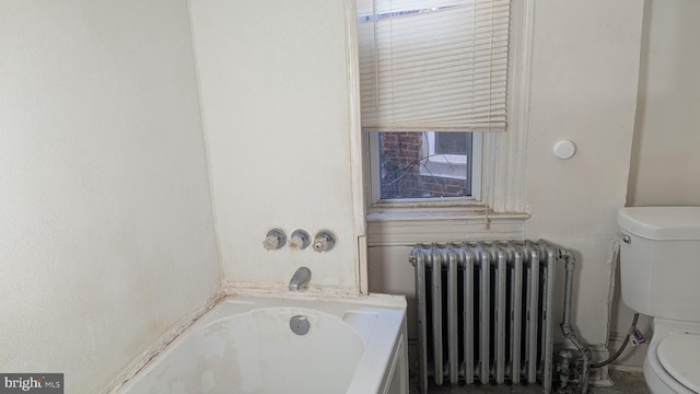 bathroom with a washtub, radiator heating unit, and toilet