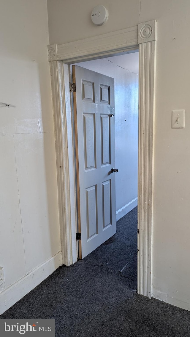 hallway with dark colored carpet