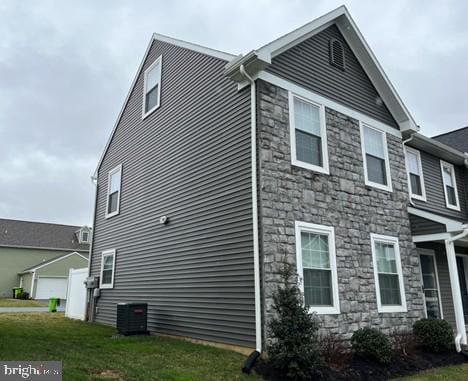 view of side of property with a garage, a yard, and central AC