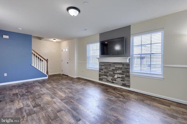 unfurnished living room featuring a healthy amount of sunlight and dark hardwood / wood-style floors