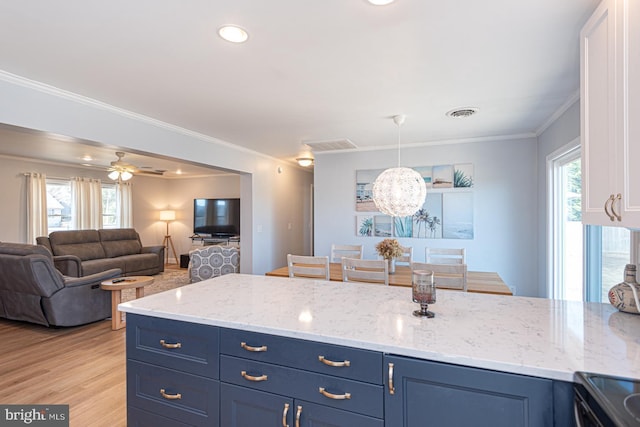 kitchen with light stone counters, hanging light fixtures, crown molding, and blue cabinets