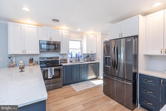 kitchen with white cabinetry, appliances with stainless steel finishes, and blue cabinetry