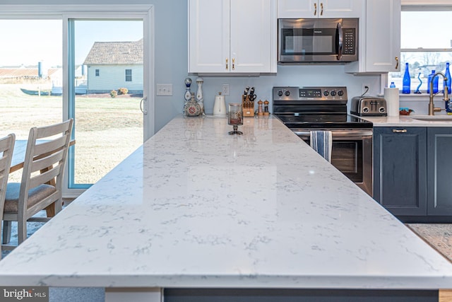 kitchen with white cabinetry, light stone countertops, plenty of natural light, and stainless steel appliances