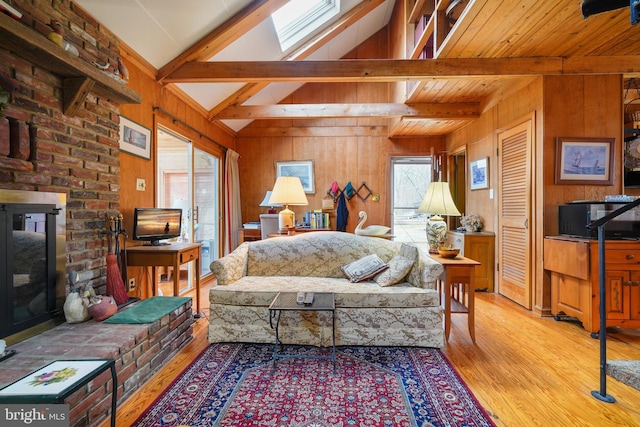 living room featuring a brick fireplace, light hardwood / wood-style flooring, vaulted ceiling with beams, and wood walls