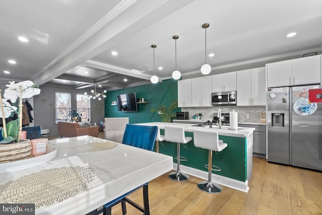 kitchen with white cabinetry, hanging light fixtures, a kitchen island with sink, stainless steel appliances, and beam ceiling