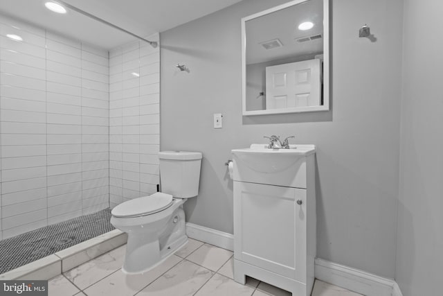 bathroom with vanity, toilet, and tiled shower