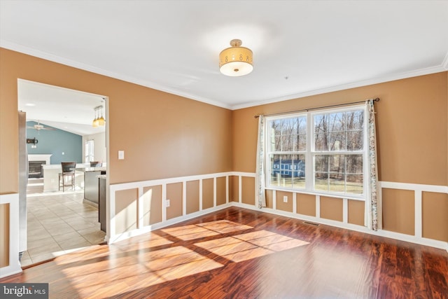 spare room with hardwood / wood-style flooring, crown molding, and vaulted ceiling