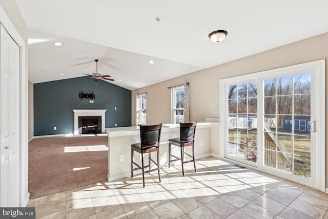 kitchen featuring a kitchen bar, vaulted ceiling, light tile patterned floors, kitchen peninsula, and ceiling fan