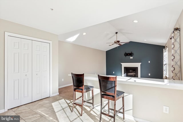 kitchen featuring ceiling fan, kitchen peninsula, vaulted ceiling, and a breakfast bar area