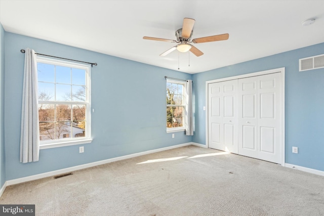 unfurnished bedroom featuring light colored carpet, a closet, and ceiling fan