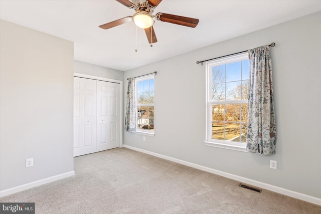 unfurnished bedroom with light colored carpet, a closet, and ceiling fan