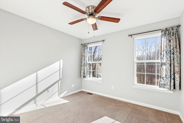 unfurnished room featuring ceiling fan, light carpet, and a wealth of natural light