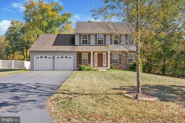 colonial inspired home featuring a garage and a front lawn