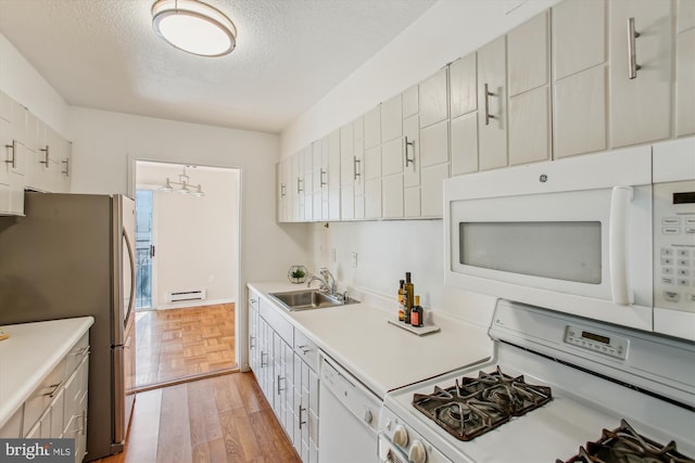 kitchen with sink, white appliances, light parquet floors, a textured ceiling, and white cabinets