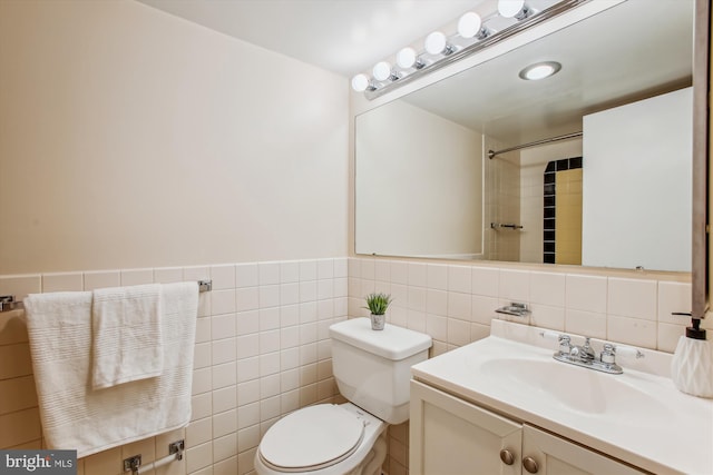 bathroom featuring vanity, tile walls, and toilet