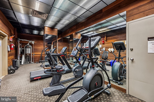 exercise room featuring carpet floors and wood walls