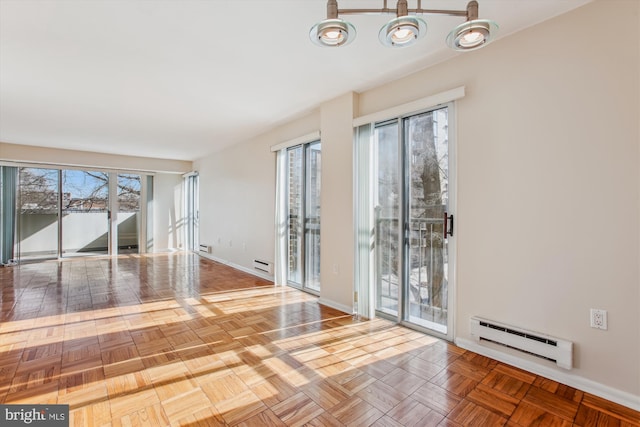 unfurnished room featuring a baseboard heating unit, parquet flooring, and plenty of natural light