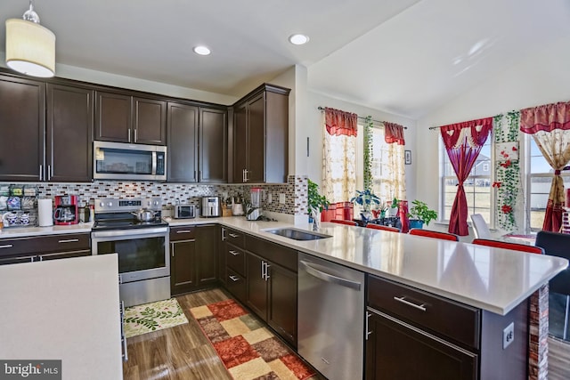 kitchen with dark hardwood / wood-style floors, pendant lighting, tasteful backsplash, sink, and stainless steel appliances