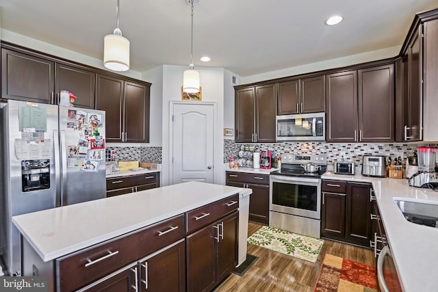 kitchen featuring pendant lighting, appliances with stainless steel finishes, backsplash, dark brown cabinets, and dark hardwood / wood-style flooring