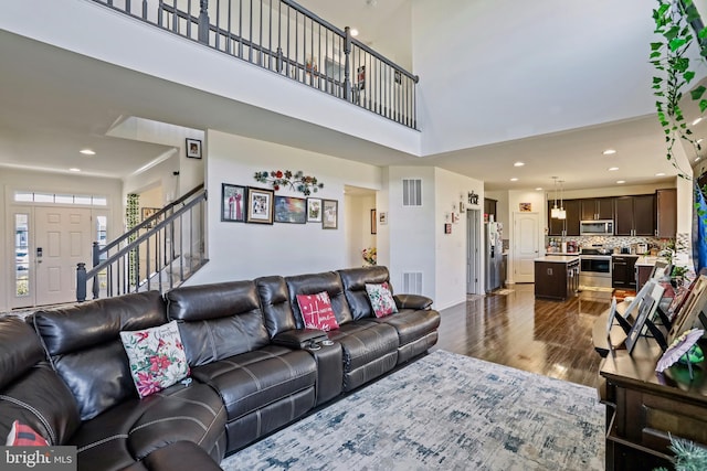 living room featuring dark hardwood / wood-style flooring and a towering ceiling