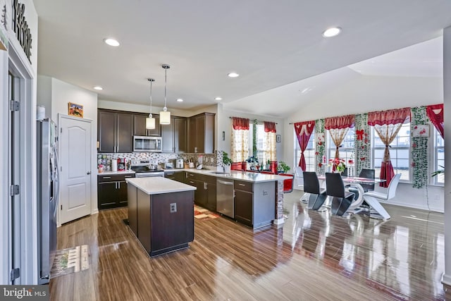 kitchen featuring dark brown cabinetry, decorative light fixtures, a kitchen island, a wealth of natural light, and stainless steel appliances