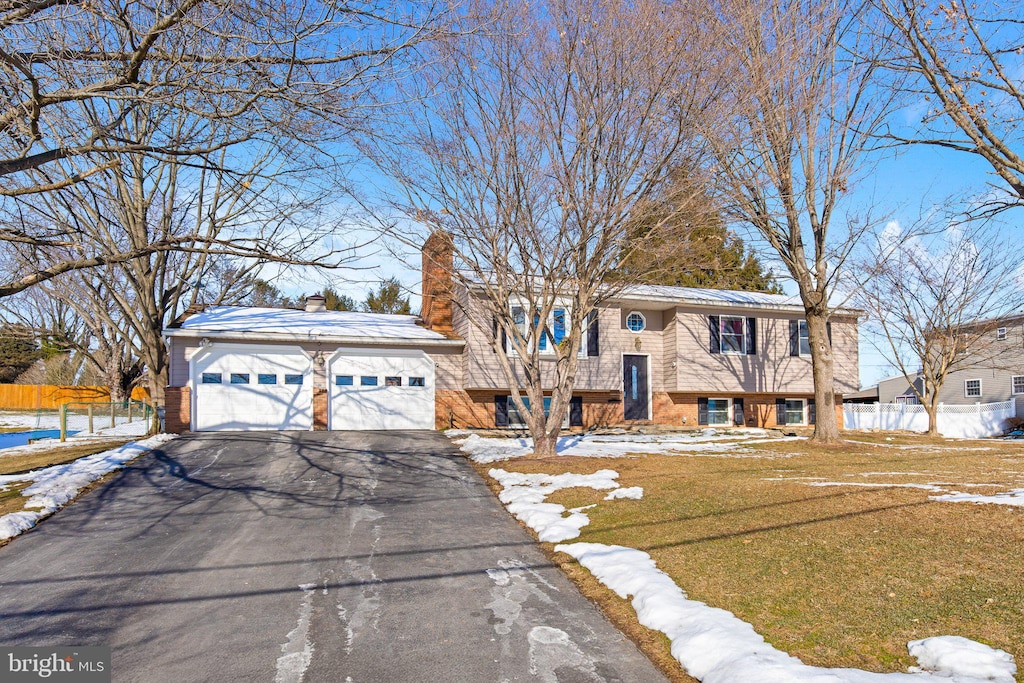 raised ranch featuring a garage and a lawn